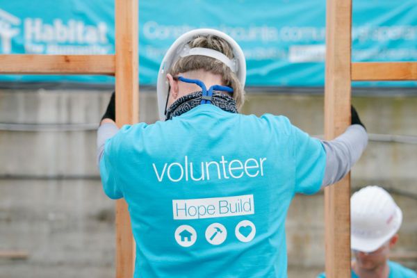 habitat volunteer standing up framed wall